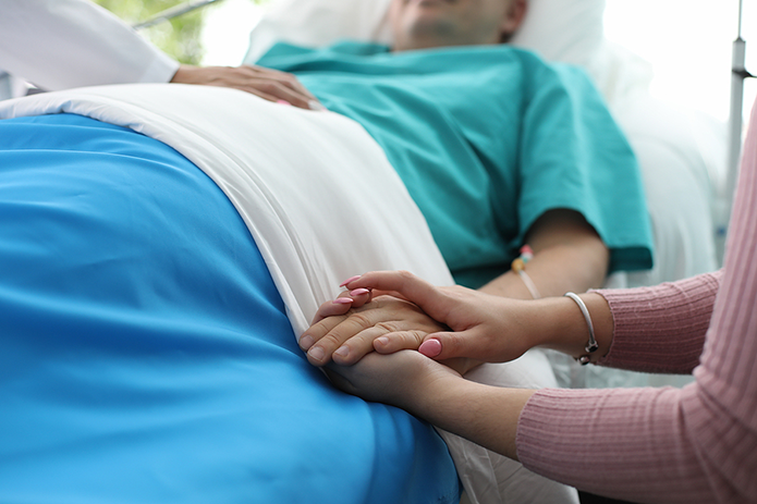 Cropped view of critically ill person holding hands with companion