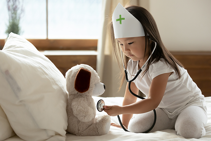 Cute little Asian girl playing doctor with her teddy bear