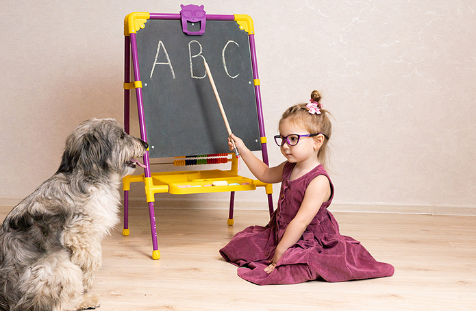 Little girl with glasses teaching her dog