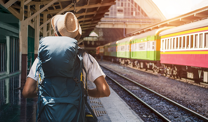 Back view of Asian man with backpack at a train station 